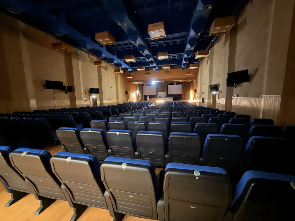 The main auditorium seen from the back, rows of blue seats facing the stage